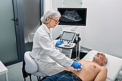 Ultraschall (Sonografie) der Bauchorgane Hier sieht man eine Ärztin, die mit einem Ultraschall die Bauchorgane eines Patienten, der auf einer Liege liegt, untersucht. Die Ultraschalluntersuchung wird auch allgemein Sonografie genannt.
